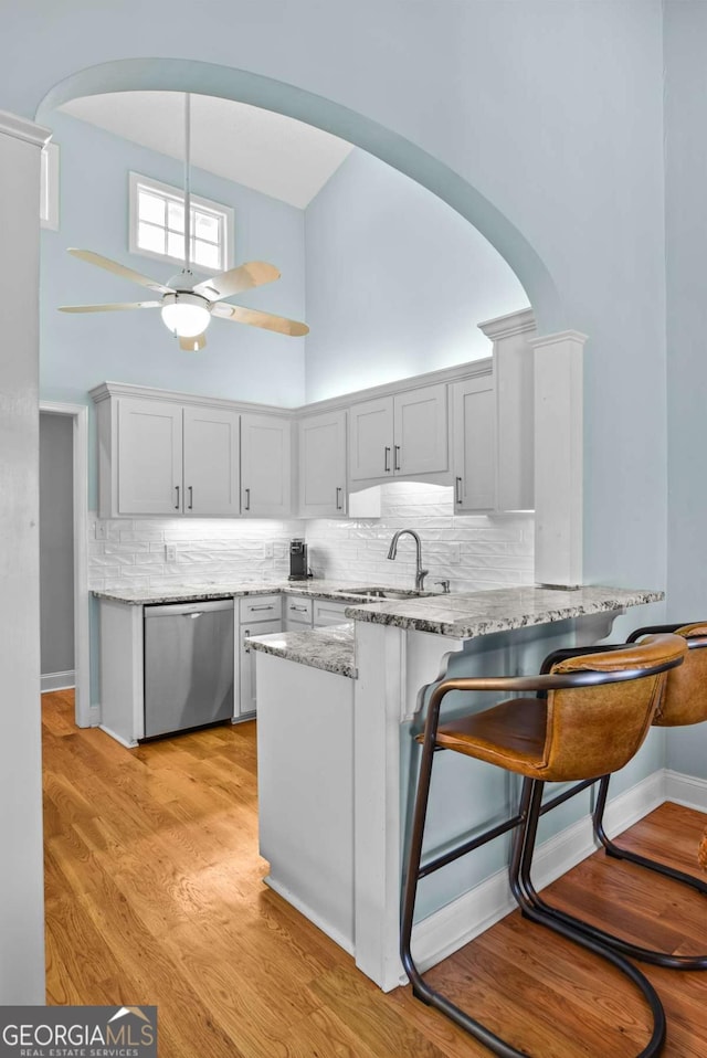 kitchen with ceiling fan, dishwasher, a towering ceiling, arched walkways, and a sink