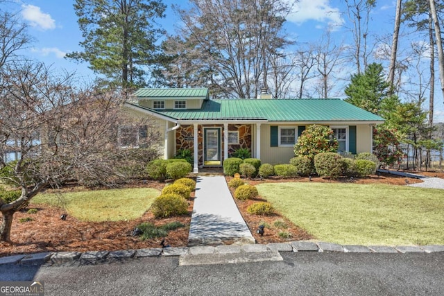 view of front of house with metal roof, a chimney, and a front lawn