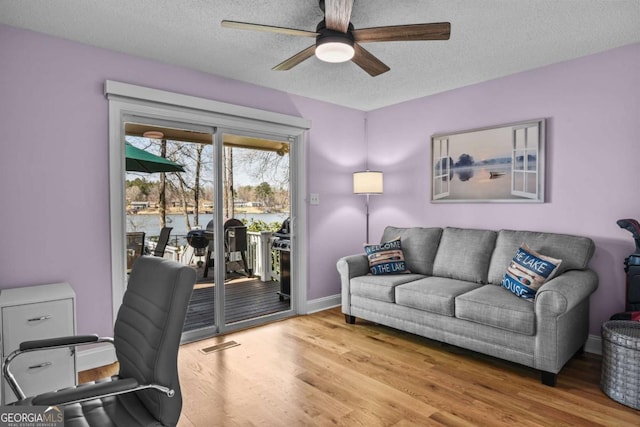 office with ceiling fan, visible vents, a textured ceiling, and wood finished floors