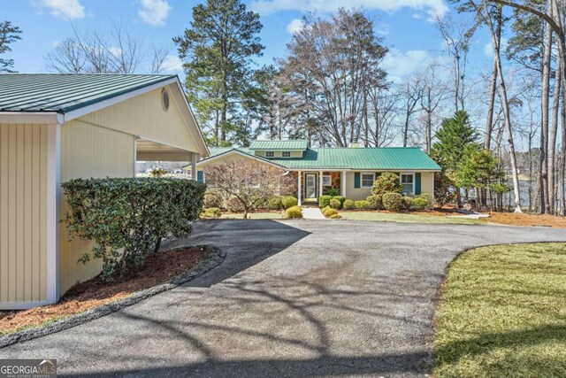 view of front of property featuring metal roof, driveway, and a standing seam roof