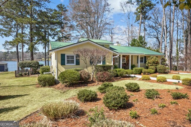 view of front of house with metal roof, a front yard, and a water view