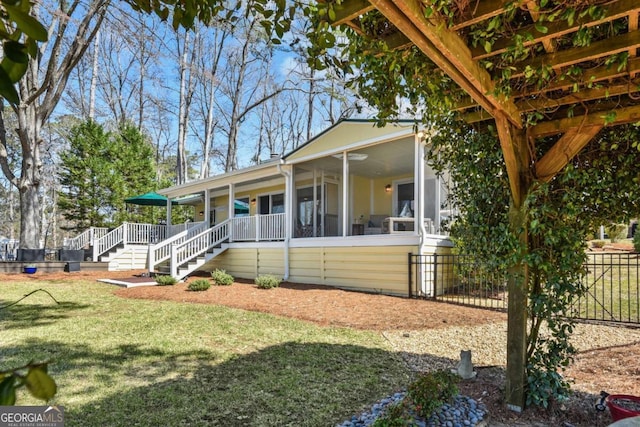 view of front of home with stairway, fence, a front lawn, and a sunroom