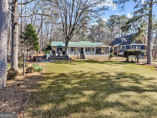 back of house with metal roof, a yard, and fence