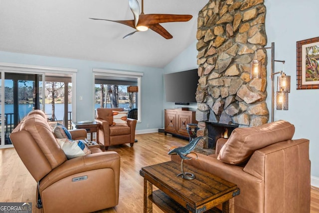 living room featuring baseboards, wood finished floors, ceiling fan, and a fireplace