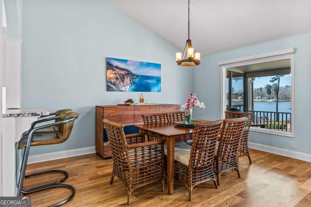 dining room with baseboards, an inviting chandelier, wood finished floors, and vaulted ceiling