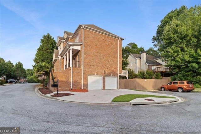 view of side of property with concrete driveway, an attached garage, and brick siding