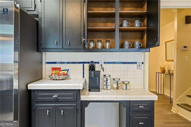 bar with decorative backsplash, baseboards, wood finished floors, and freestanding refrigerator