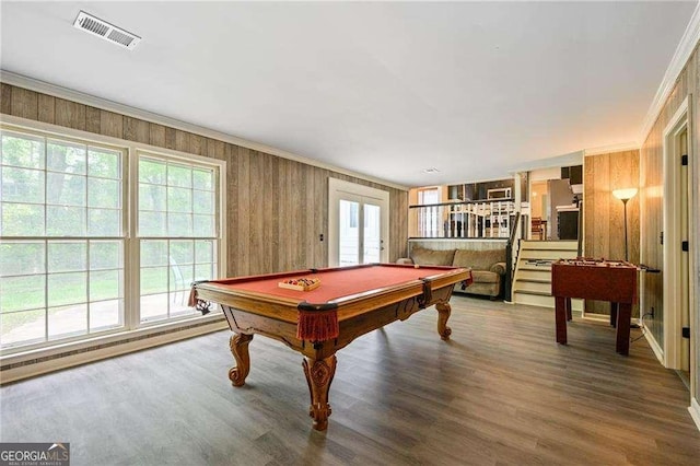 rec room with crown molding, plenty of natural light, wood finished floors, and visible vents