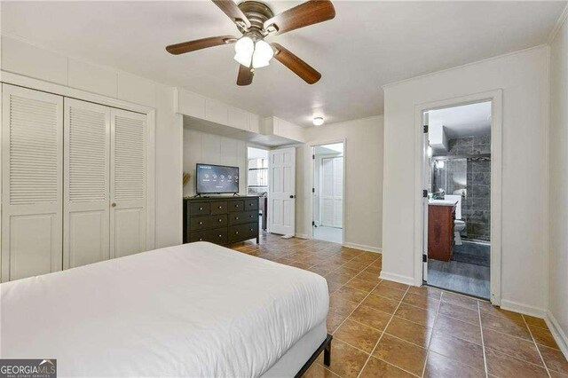 tiled bedroom featuring a closet, baseboards, ensuite bath, and a ceiling fan