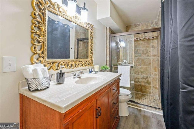 full bath featuring vanity, toilet, wood finished floors, and a stall shower