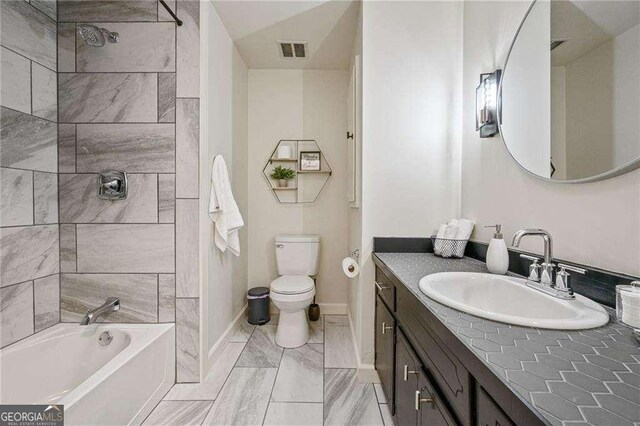 full bathroom with visible vents, toilet,  shower combination, baseboards, and vanity