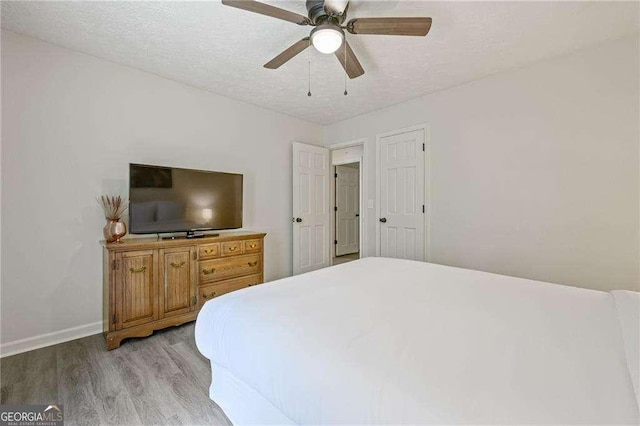 bedroom with light wood finished floors, baseboards, a textured ceiling, and ceiling fan