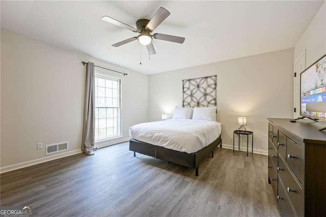 bedroom featuring ceiling fan, visible vents, baseboards, and wood finished floors