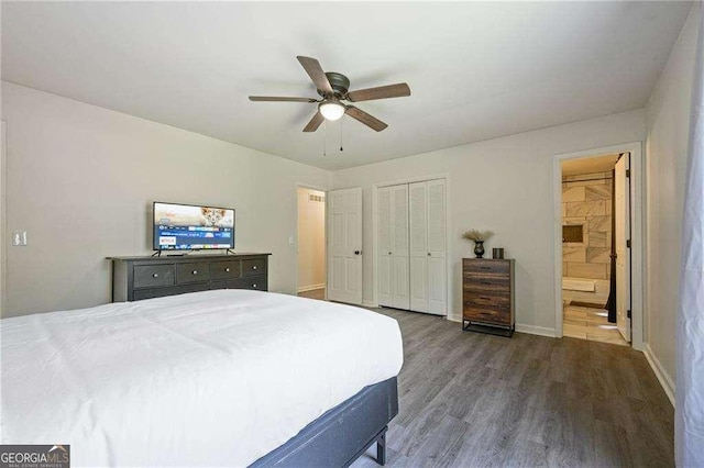 bedroom featuring a ceiling fan, ensuite bath, a closet, baseboards, and dark wood-style flooring