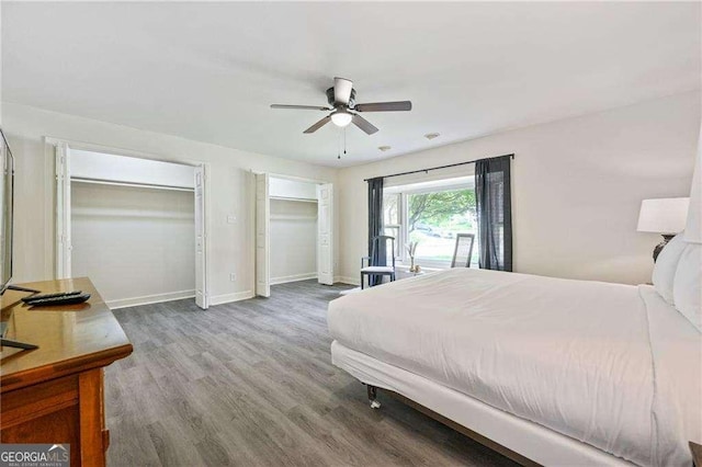 bedroom featuring baseboards, multiple closets, wood finished floors, and a ceiling fan
