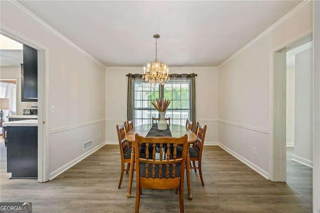 dining area featuring a notable chandelier, crown molding, visible vents, and wood finished floors