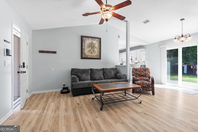 living room featuring visible vents, light wood-style flooring, ceiling fan with notable chandelier, and vaulted ceiling