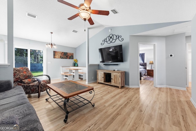 living area with vaulted ceiling, light wood-style flooring, ceiling fan with notable chandelier, and visible vents