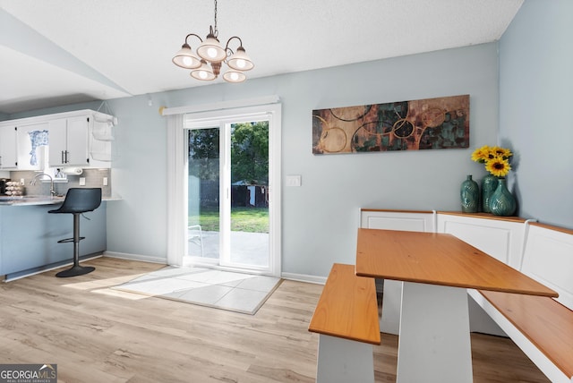 dining room with vaulted ceiling, baseboards, light wood-type flooring, and a chandelier