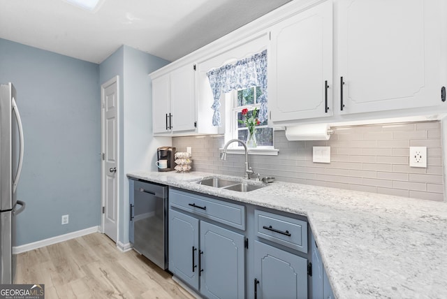 kitchen featuring backsplash, light wood-type flooring, white cabinets, stainless steel appliances, and a sink