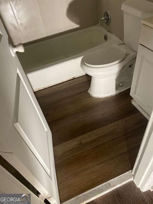 bathroom with a tub, toilet, vanity, and wood finished floors