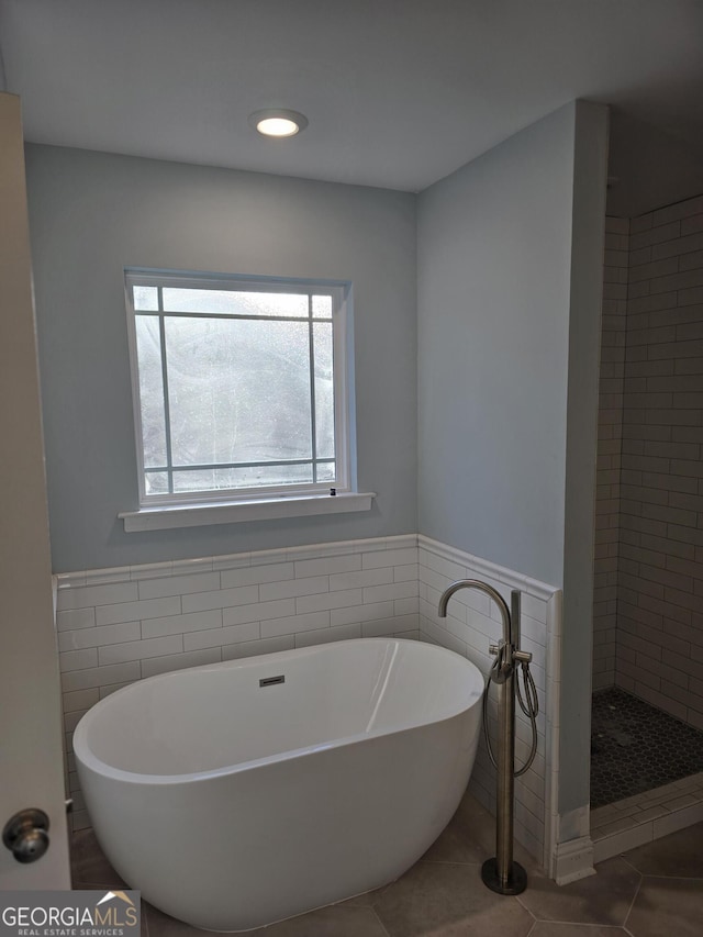 full bathroom featuring tile patterned floors, tile walls, a wainscoted wall, and a freestanding bath