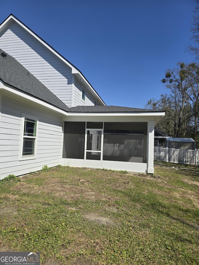 rear view of property with a yard, fence, a sunroom, and a shingled roof