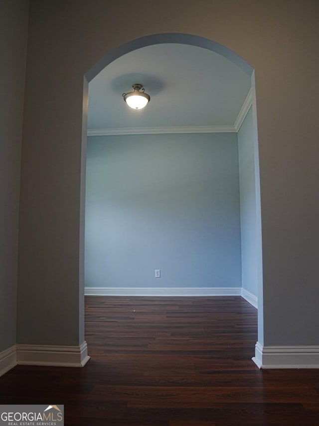 unfurnished room featuring crown molding, wood finished floors, arched walkways, and baseboards