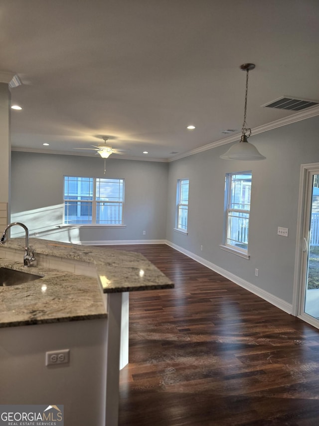 kitchen featuring light stone counters, visible vents, crown molding, and a sink