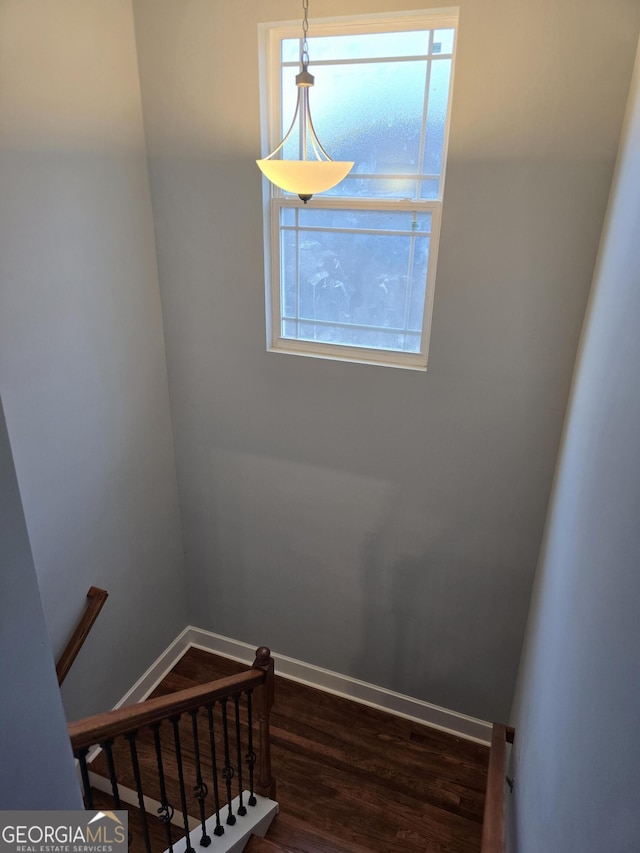 staircase featuring wood finished floors and baseboards