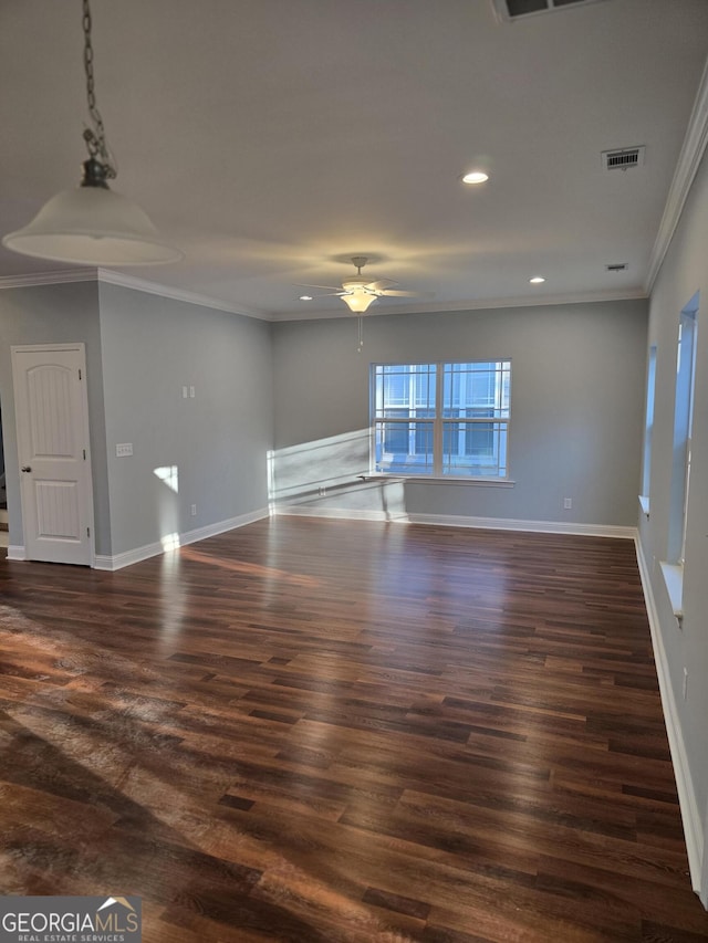 unfurnished room with visible vents, dark wood-type flooring, ornamental molding, baseboards, and ceiling fan