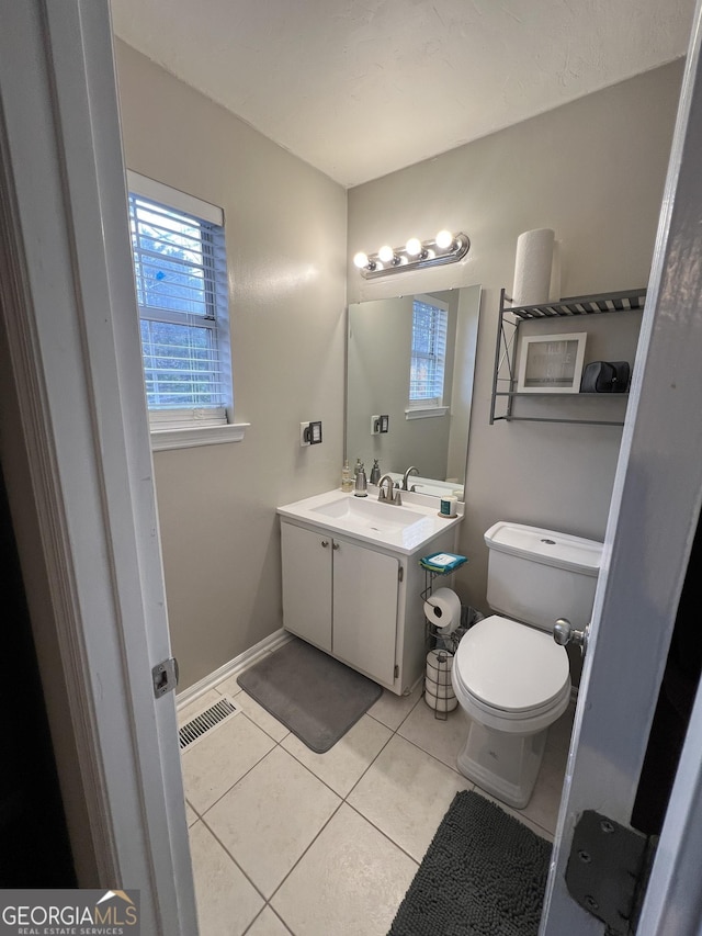 bathroom with visible vents, baseboards, toilet, tile patterned floors, and vanity