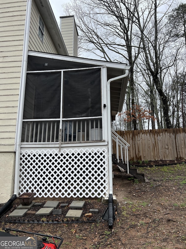 view of side of property featuring fence and a sunroom