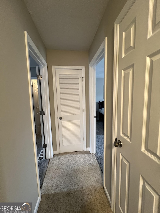 hallway featuring baseboards and carpet flooring