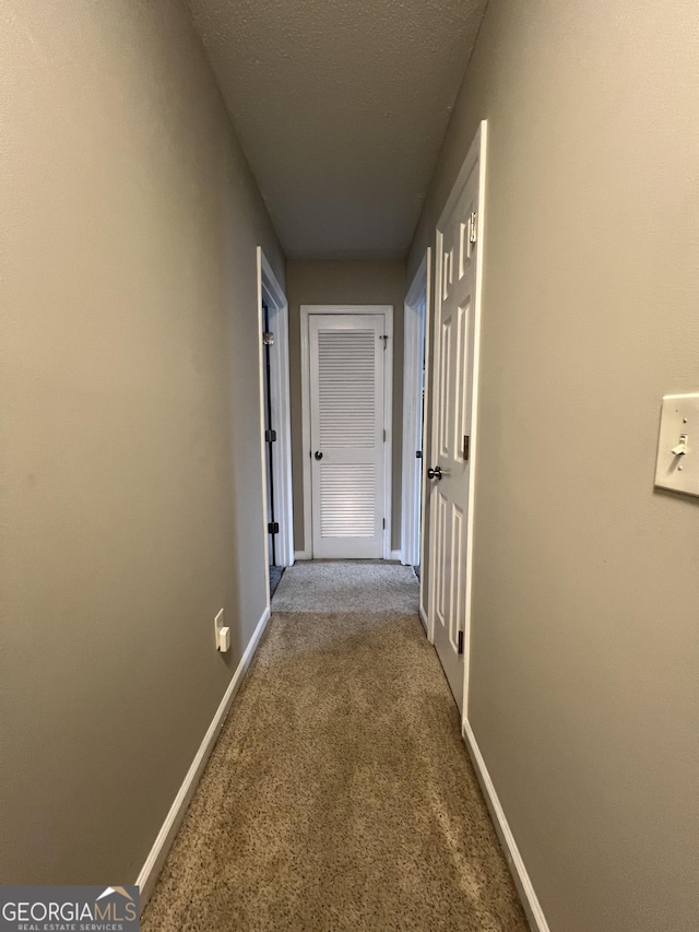 corridor with carpet flooring, baseboards, and a textured ceiling