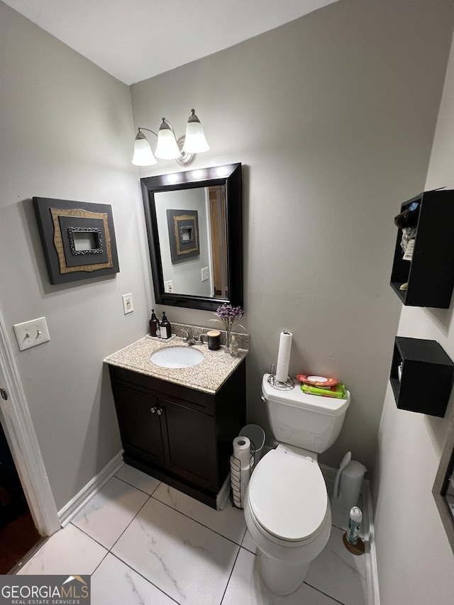 half bathroom with marble finish floor, toilet, vanity, and baseboards