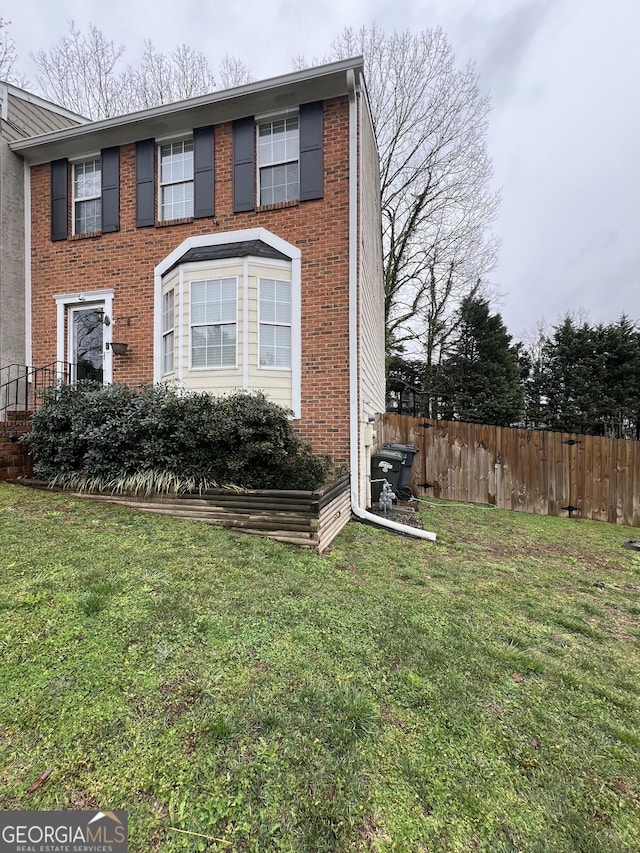 view of front of property with a front yard, fence, and brick siding