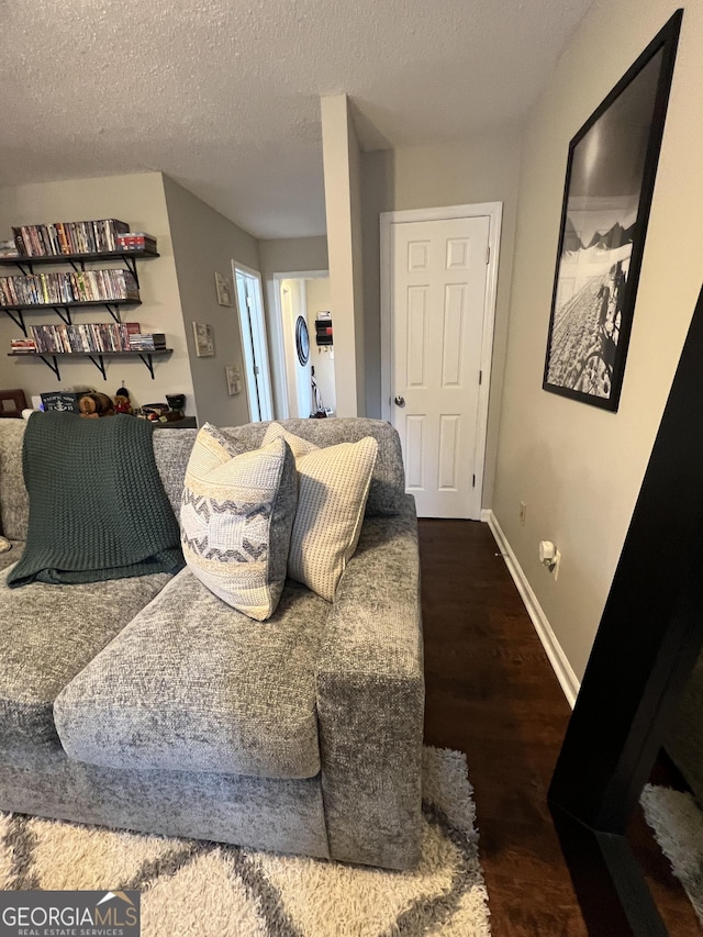 living area with a textured ceiling, baseboards, and wood finished floors