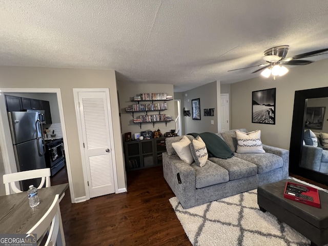 living room featuring dark wood-type flooring, ceiling fan, and a textured ceiling