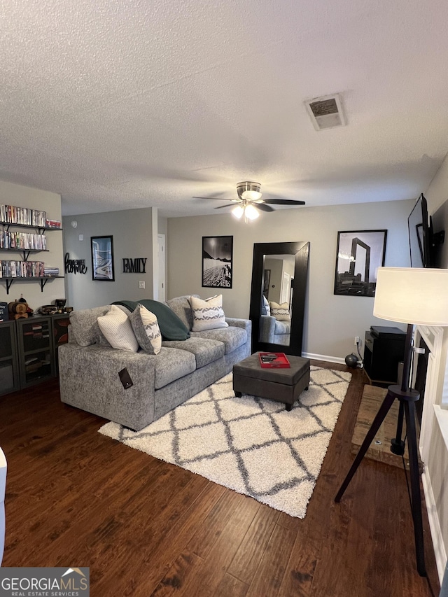 living area with visible vents, a textured ceiling, ceiling fan, and wood finished floors