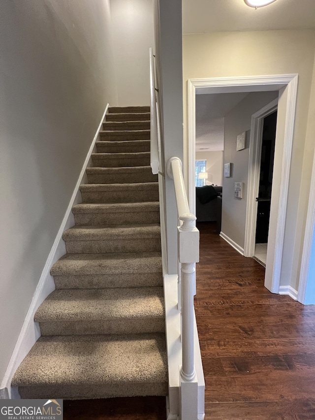 staircase with baseboards and wood finished floors