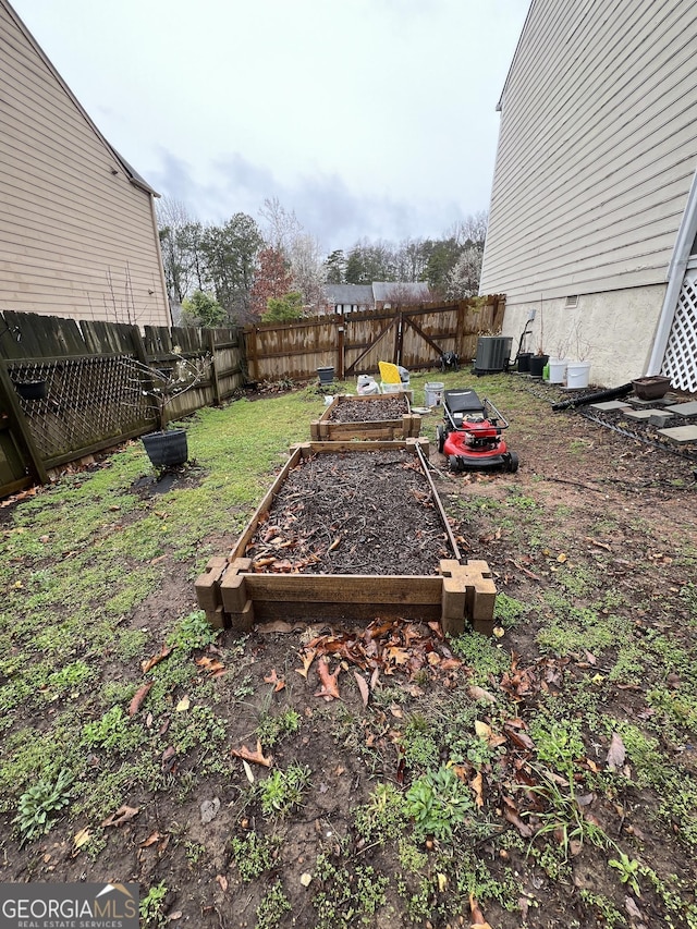 view of yard featuring a garden, central AC unit, and a fenced backyard