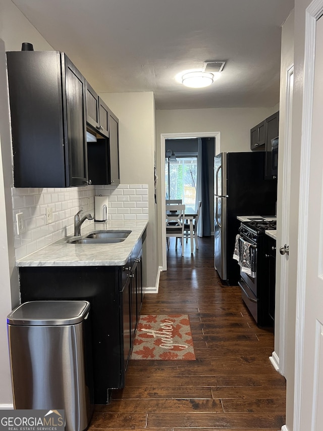 kitchen featuring visible vents, dark wood-type flooring, a sink, gas stove, and light countertops