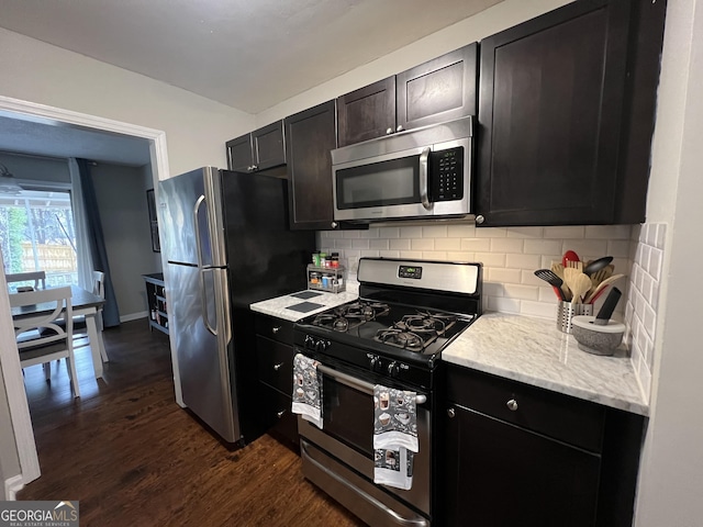 kitchen featuring backsplash, dark wood-style floors, appliances with stainless steel finishes, baseboards, and light stone countertops