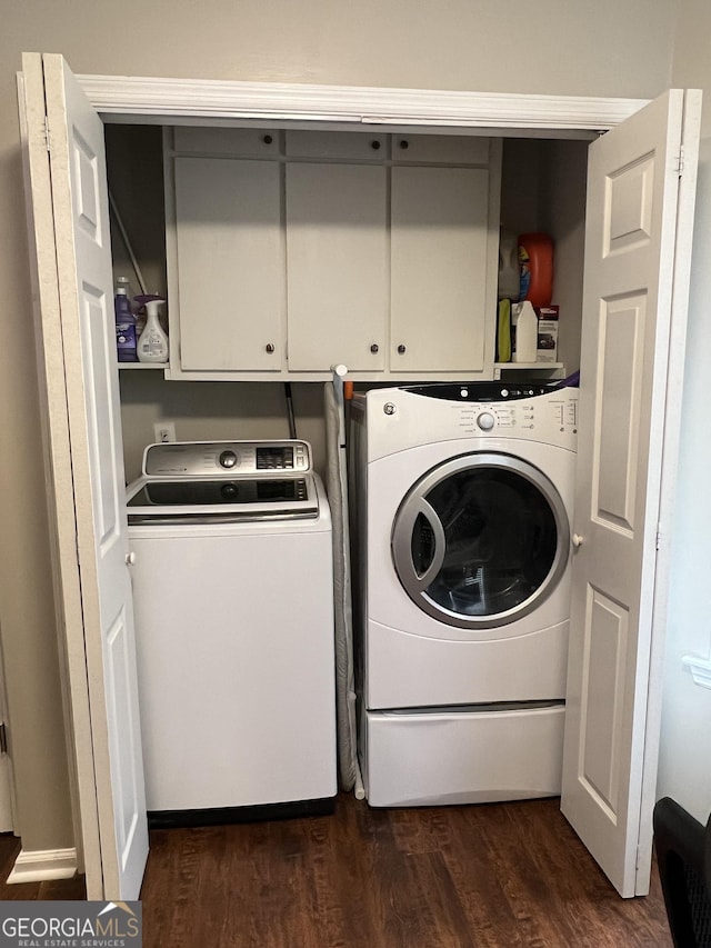 washroom featuring cabinet space, washer and dryer, and dark wood-type flooring