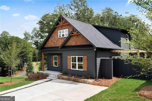 craftsman house featuring a shingled roof, a front lawn, and fence