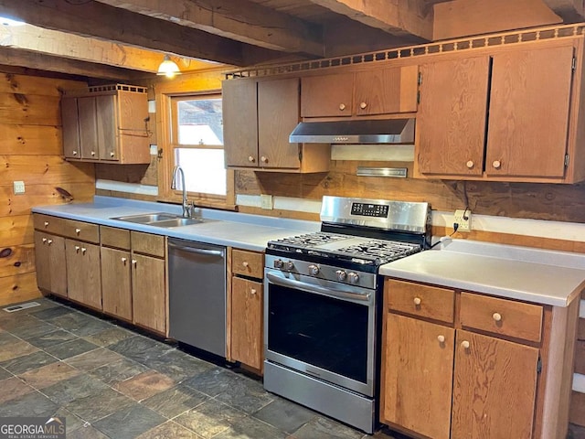 kitchen featuring wooden walls, beam ceiling, a sink, under cabinet range hood, and appliances with stainless steel finishes