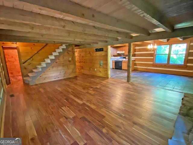 interior space with wood finished floors, beam ceiling, an inviting chandelier, stairs, and wood walls