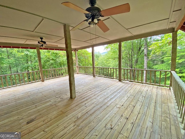 wooden deck with a view of trees and ceiling fan