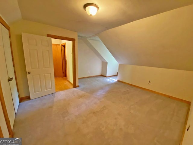 additional living space with lofted ceiling, light colored carpet, and baseboards